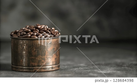 Roasted coffee beans fill a rustic metal container against a dark background, showcasing a rich aroma and inviting coffee experience. 128684398