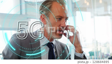 Image of 5g over caucasian senior businessman using smartphone in office 128684895