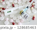 Vial of Covid-19 vaccine, 1 ml plastic syringe with needle, positive test result of Covid-19 antigen test kit and drugs isolated on the white background 128685463