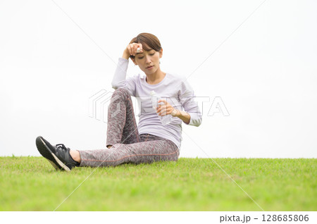 芝生で水分補給をする女性 128685806