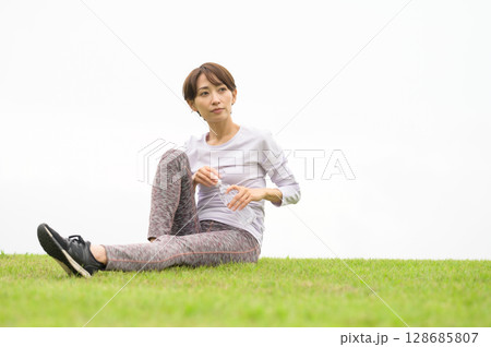 芝生で水分補給をする女性 128685807
