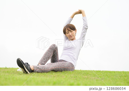 芝生の上でストレッチをする女性 128686034