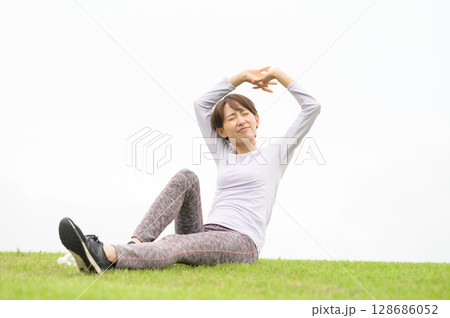 芝生の上でストレッチをする女性 芝生の上でストレッチをする女性 128686052