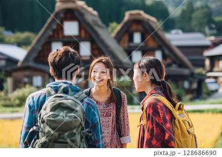 秋の白川郷を旅する若者たち|笑顔あふれる古民家前でのひととき 秋の白川郷を旅する若者たち|笑顔あふれる古民家前でのひととき 128686690