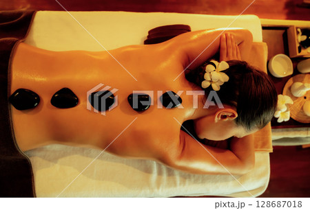 Hot stone massage at spa salon in luxury resort with warm candle light.Quiescent Hot stone massage at spa salon in luxury resort with warm candle light.Quiescent 128687018
