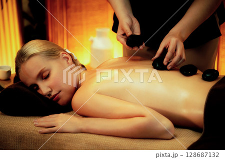 Hot stone massage at spa salon in luxury resort with warm candle light.Quiescent Hot stone massage at spa salon in luxury resort with warm candle light.Quiescent 128687132