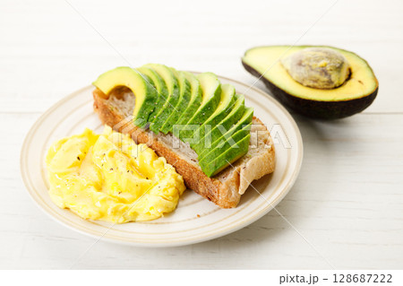 Healthy simple breakfast toast with sliced avocado and scrambled egg. 128687222