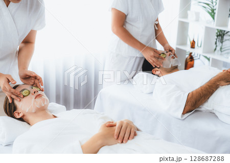 Couple customer indulges in rejuvenating with cucumber facial care. Quiescent Couple customer indulges in rejuvenating with cucumber facial care. Quiescent 128687288