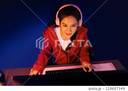 Host channel Asian streamer concentrating game wearing headphone. Stratagem. Host channel Asian streamer concentrating game wearing headphone. Stratagem. 128687349