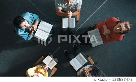 Top down view of prayers reading bible while making folded hands. Symposium. Top down view of prayers reading bible while making folded hands. Symposium. 128687478