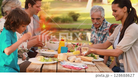 Image of light spots over caucasian family eating dinner outdoors 128688627