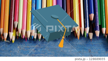 Image of mortarboard moving over coloured pencils on desk 128689035