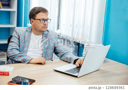Business man in glasses working on laptop online in library 128689361