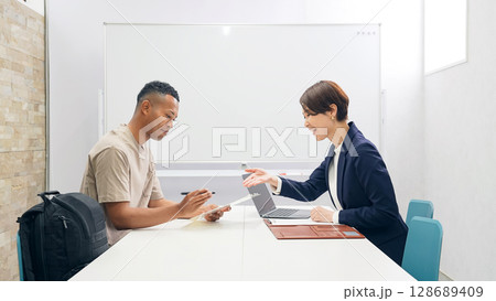 面談する黒人男性と日本人女性スタッフ 128689409