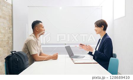 面談する黒人男性と日本人女性スタッフ 128689410