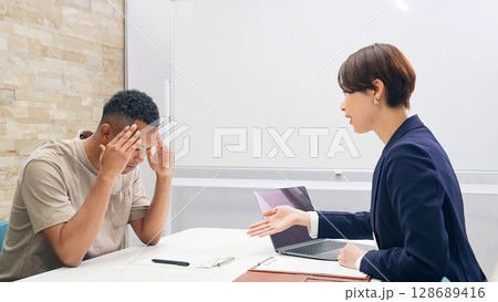悩む黒人男性と面談する日本人女性スタッフ 128689416