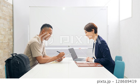 面談する黒人男性と日本人女性スタッフ 128689419