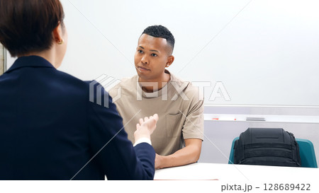 面談する黒人男性と日本人女性スタッフ 128689422