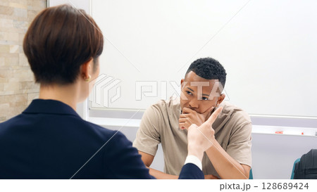 悩む黒人男性と面談する日本人女性スタッフ 悩む黒人男性と面談する日本人女性スタッフ 128689424