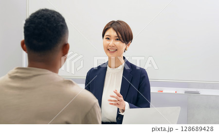黒人男性と面談する日本人女性スタッフ 黒人男性と面談する日本人女性スタッフ 128689428
