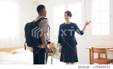 黒人男性旅行客に部屋を案内する女性ホテルスタッフ 128689432