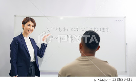 黒人男性に日本語学校でビジネス用語を教える女性教師 128689435