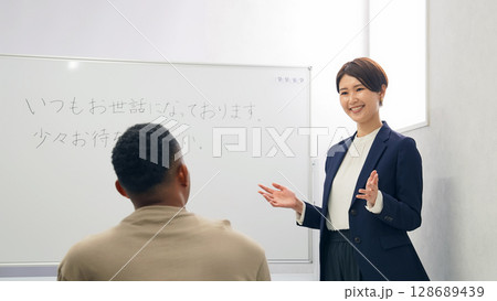 黒人男性に日本語学校でビジネス用語を教える女性教師 128689439