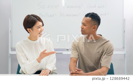 教室で会話する黒人男性と日本人女性 教室で会話する黒人男性と日本人女性 128689442