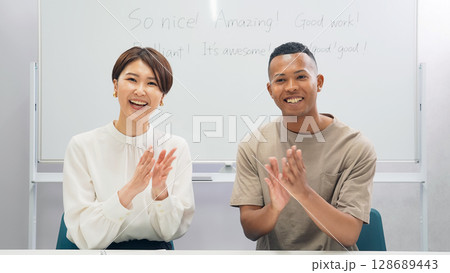 教室で拍手する黒人男性と日本人女性 教室で拍手する黒人男性と日本人女性 128689443