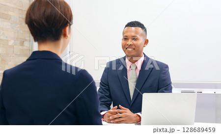黒人男性ビジネスマンと面談する日本人女性スタッフ 128689459