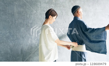 着付け師に浴衣の着付けをしてもらう黒人男性 着付け師に浴衣の着付けをしてもらう黒人男性 128689479