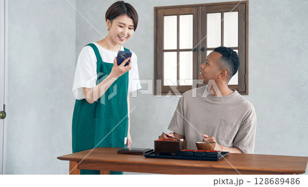 スマホの翻訳アプリで黒人男性に接客する飲食店店員 128689486