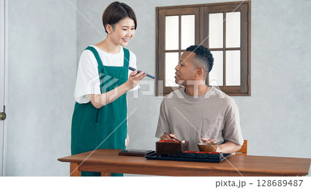 スマホの翻訳アプリで黒人男性に接客する飲食店店員 128689487