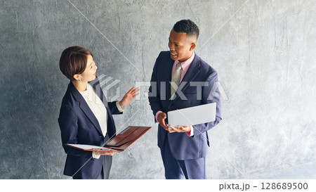 おしゃれな部屋で会話する黒人男性ビジネスマンと日本人女性スタッフ 128689500