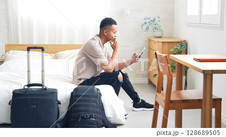 ホテルの部屋でスマホを見る黒人男性旅行者 128689505