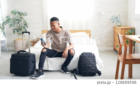ホテルの部屋でスマホを見る黒人男性旅行者 128689506
