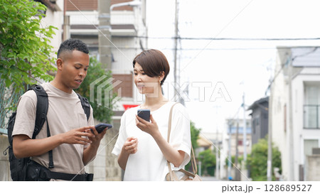 スマホの翻訳アプリを使って黒人男性と会話する日本人女性 スマホの翻訳アプリを使って黒人男性と会話する日本人女性 128689527