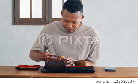 飲食店で鰻重を食べる黒人男性 128689537