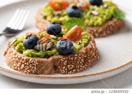 Avocado toast with blueberries, cherry tomatoes, sunflower seeds, pumpkin seeds and sesame seed Avocado toast with blueberries, cherry tomatoes, sunflower seeds, pumpkin seeds and sesame seed 128689592