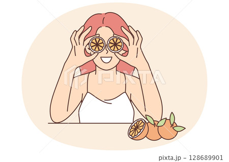 Woman holds slices of citrus fruit near eyes offering to use orange for rejuvenating facial mask Woman holds slices of citrus fruit near eyes offering to use orange for rejuvenating facial mask 128689901
