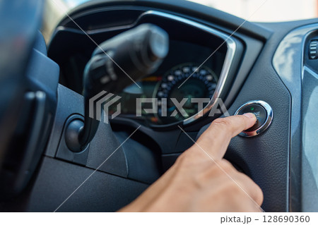 Close-up of hand pressing start button to turn on car engine. Keyless ignition system in modern car 128690360