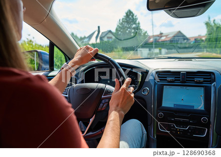 Woman driving modern car with GPS navigation on screen, hands on steering wheel. Concept of modern travel, road trip and smart vehicle technology 128690368