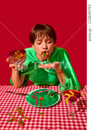 Woman with closed eyes joyfully stuffing gummy worms into mouth at vibrant dessert table Woman with closed eyes joyfully stuffing gummy worms into mouth at vibrant dessert table 128690703
