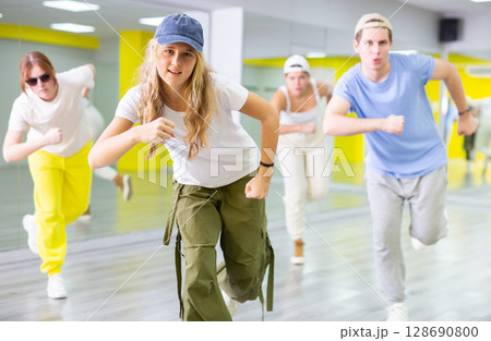 Teenage girl in cap training breakdance Toprock moves in dance hall 128690800