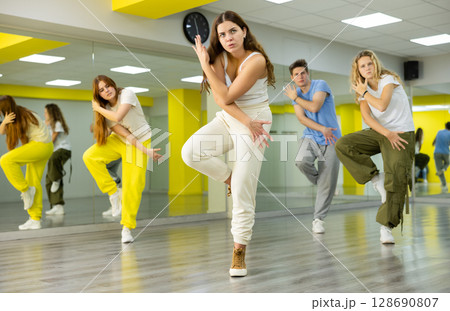 Class of expressive teenagers dancing and practicing new movements in dance hall. Sport, dance and urban culture concept 128690807