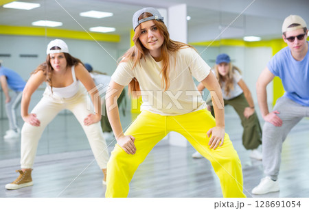 Teenage dancers, young people practicing modern dance styles in their rehearsal moves in studio with mirrors 128691054