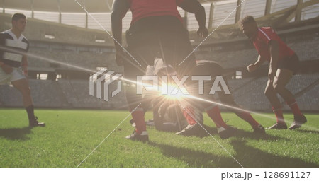 Image of spots lights moving over diverse team of rugby players during game in field 128691127