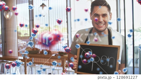 Smiling Chinese man holding chalkboard sign reading Open in cafe, with virus particles, copy space 128691227