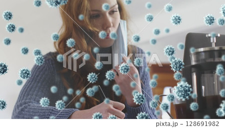Writing woman adjusting face mask and noting in notebook at kitchen table, with coffee mug Writing woman adjusting face mask and noting in notebook at kitchen table, with coffee mug 128691982
