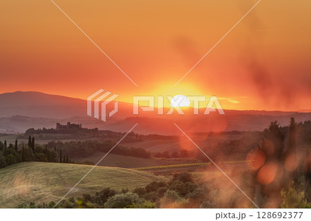 Tuscan sunset bathes rolling hills and a distant castle in golden light Tuscan sunset bathes rolling hills and a distant castle in golden light 128692377
